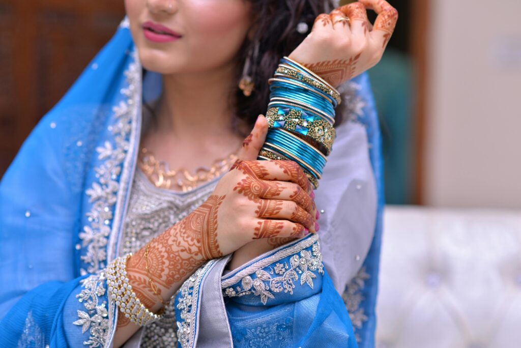 pexels-photo-1297483-1297483 A bride showcases intricate henna designs and vibrant jewelry in traditional attire.