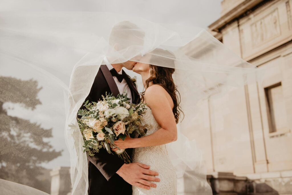 pexels-photo-2253870-2253870 Bride and groom share a tender kiss under a veil, showcasing love and romance on their special day.